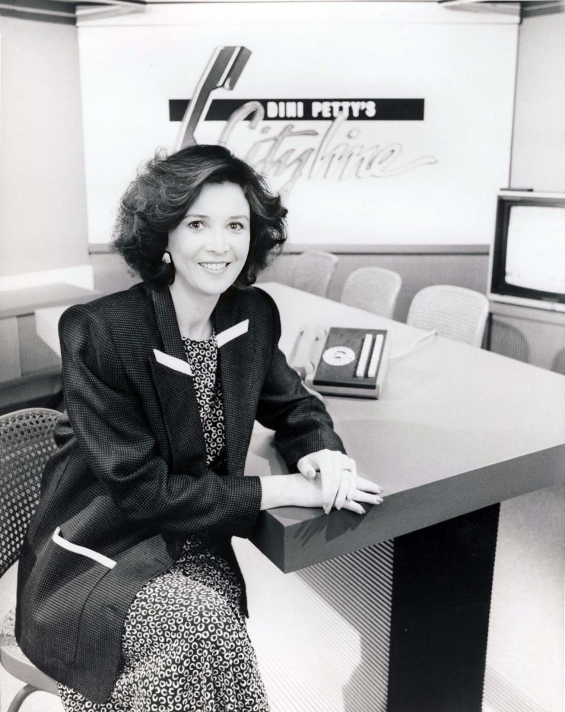 Black and white photo of Dini Petty seated on the set of her Citytv television show